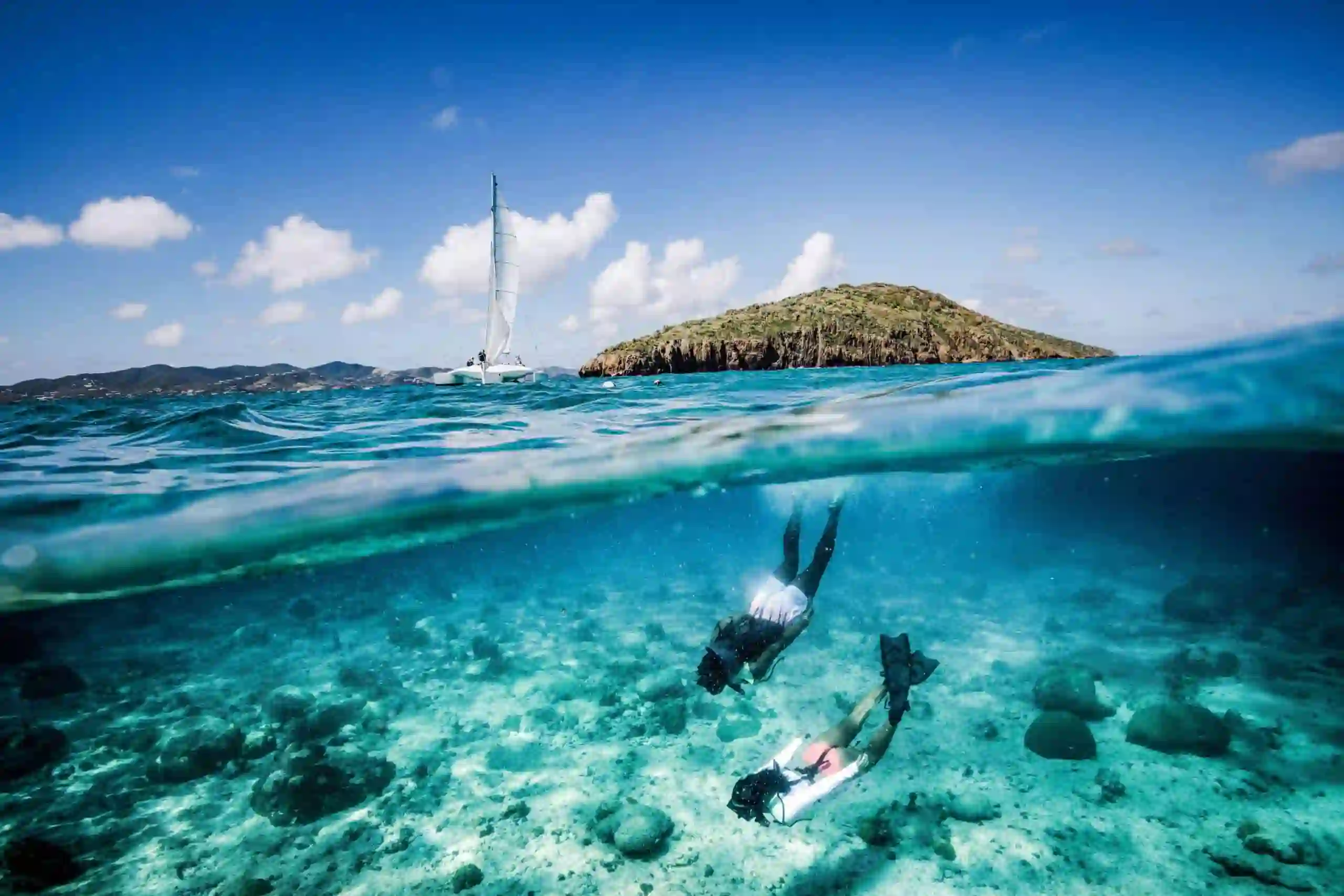 Catamaran anchored off the white sand beach of Buck Island near St. Croix with clear turquoise water
