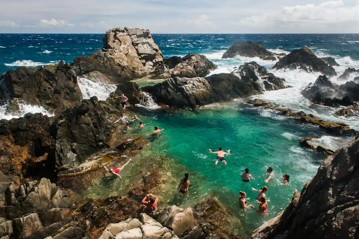 The Natural Pool, Conchi, a rock-enclosed saltwater pool with waves crashing over the rocks in Arikok National Park, Aruba