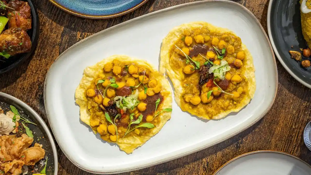 Trinidadian doubles, curried chickpeas between two fried bara breads, wrapped in paper at a street stall