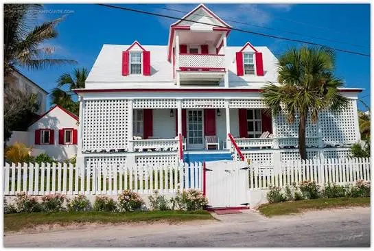 Pastel-colored clapboard cottages with white picket fences on a quiet street in Dunmore Town, Harbour Island