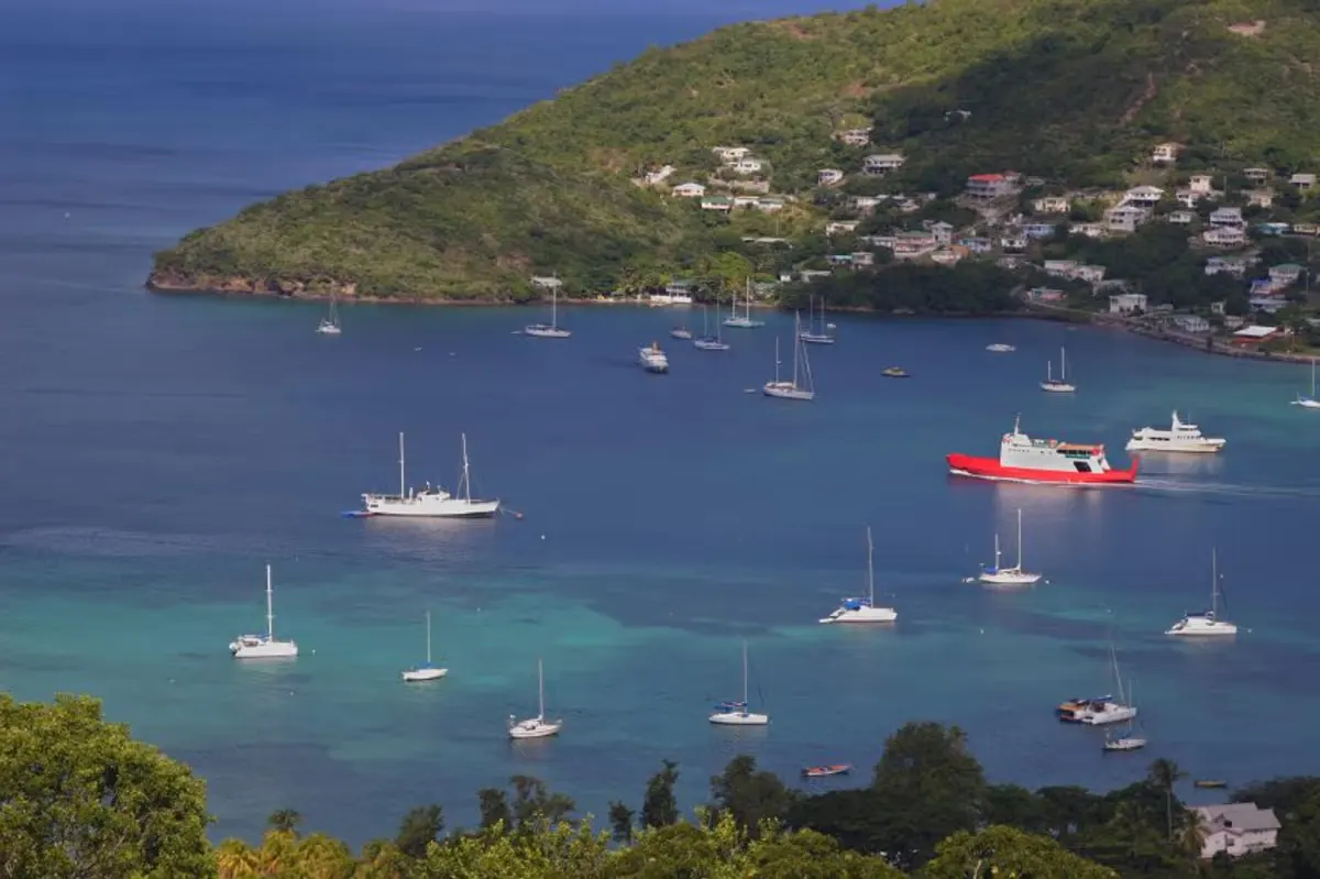 Wide curving beach at Friendship Bay on Bequia's south coast with fishing boats and hills behind