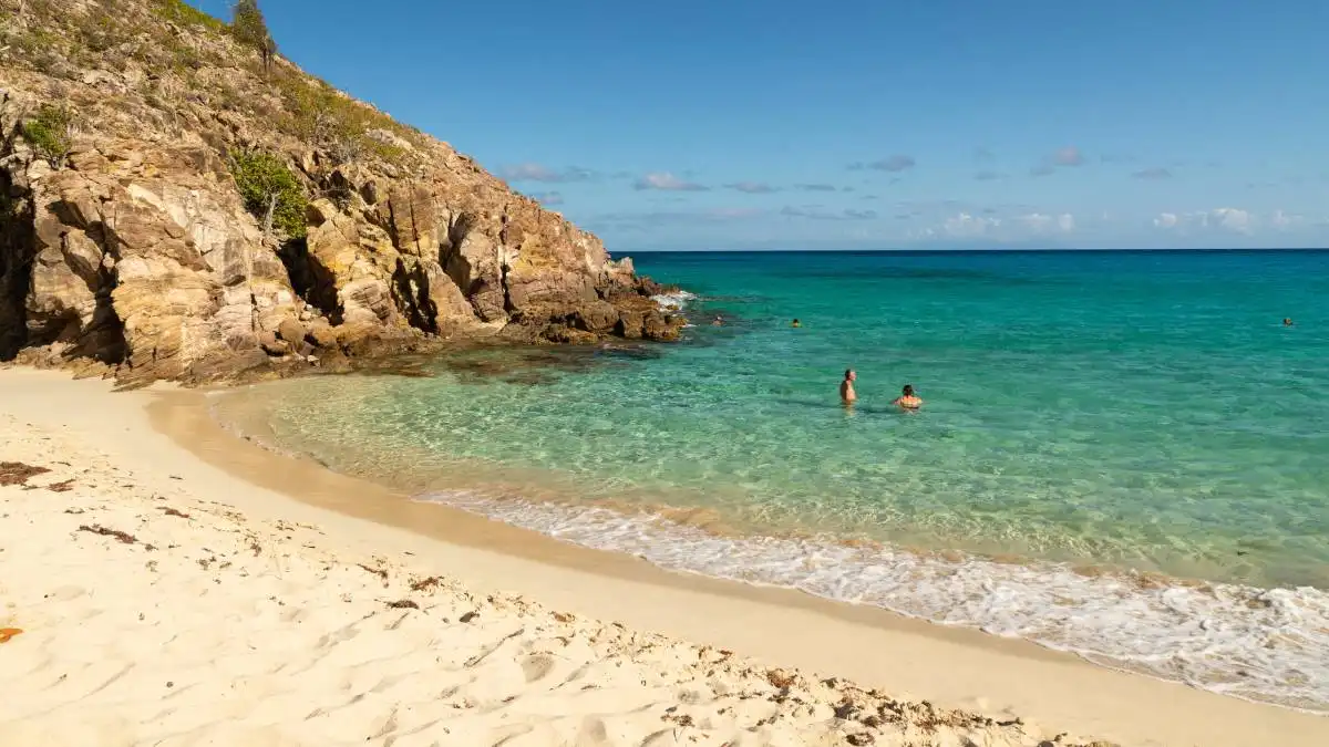 Secluded Gouverneur Beach in Saint Barthelemy with steep green hills and calm clear water