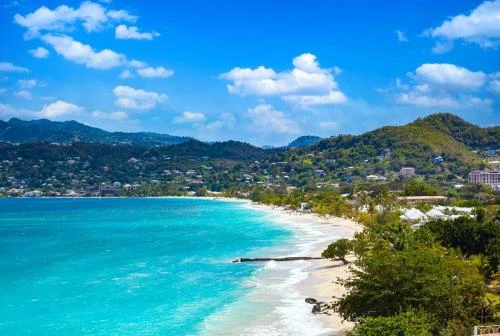 Long white sand beach at Grand Anse, Grenada, with calm water and St. George's in the distance