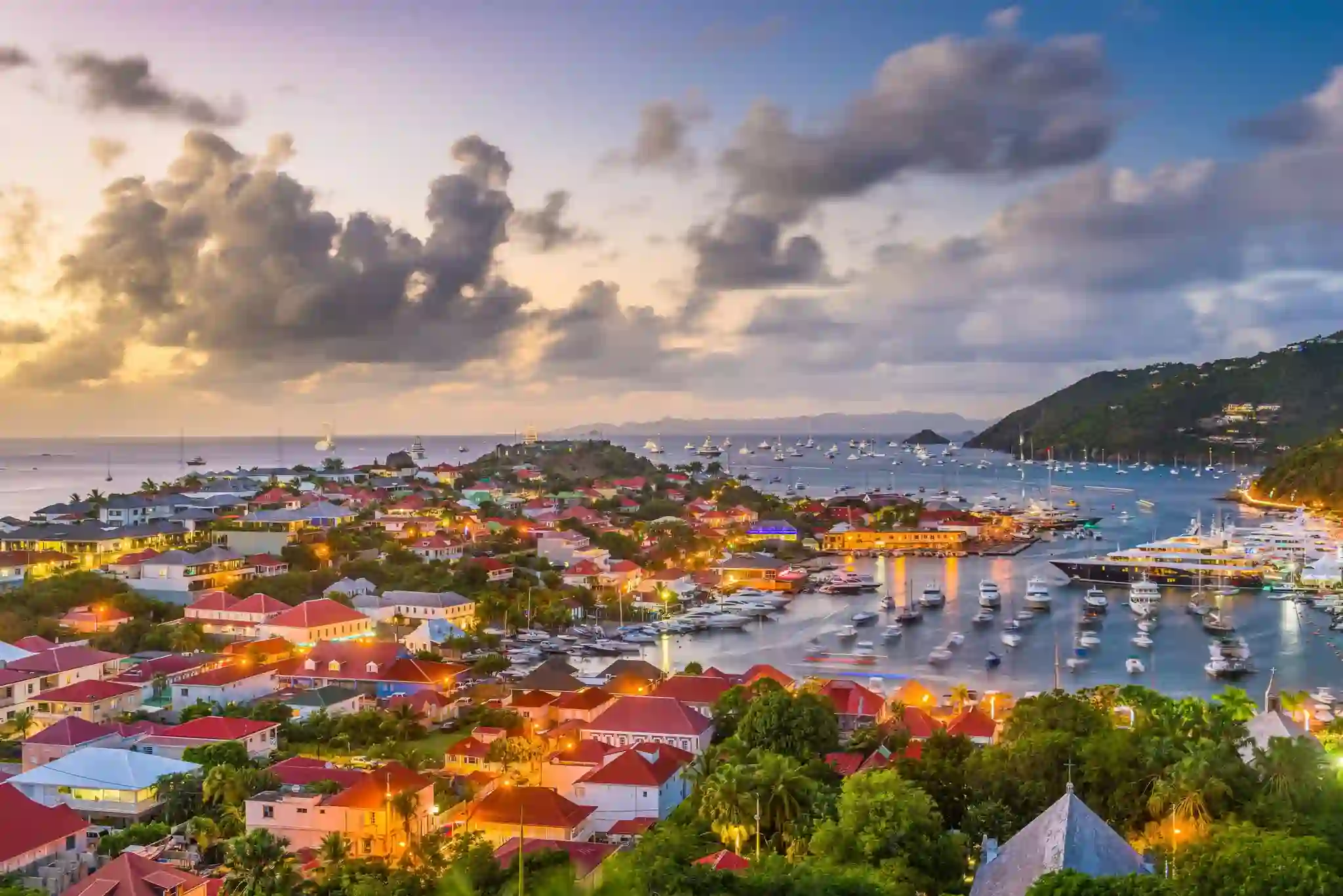 Aerial view of Gustavia harbour in Saint Barthelemy with red-roofed buildings, yachts and green hills