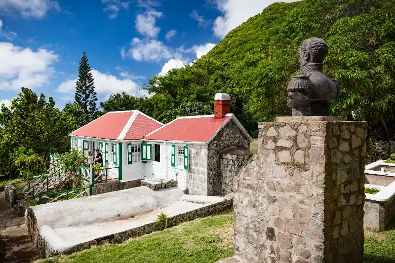 Traditional white Saban cottage with green shutters and a red roof housing the Harry L. Johnson Museum in Windwardside