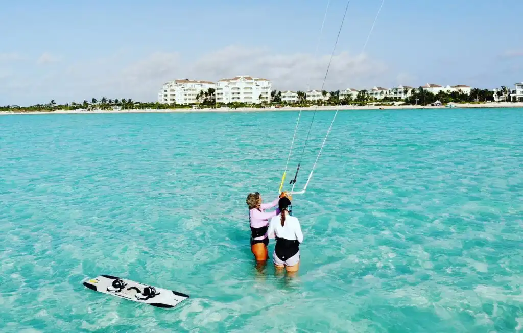 Kitesurfers gliding across shallow turquoise water at Long Bay Beach, Providenciales