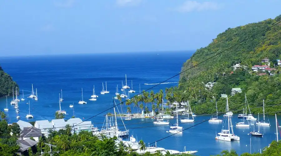 Yachts anchored in the sheltered green bay of Marigot Bay, Saint Lucia, surrounded by palm trees and hills