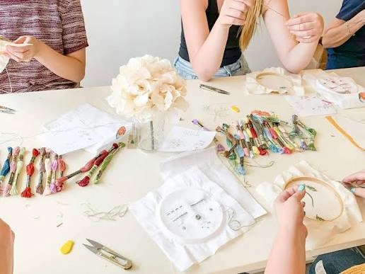 Close-up of hands creating intricate Saba Lace drawn-thread embroidery on white fabric