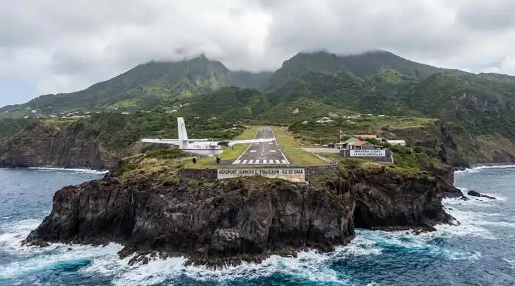 The steep green volcanic island of Saba rising from the sea, with Mount Scenery's summit in the clouds