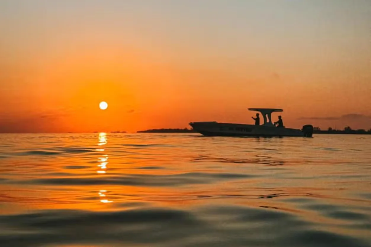 People watching the sunset from a wooden dock bar over the water in Utila