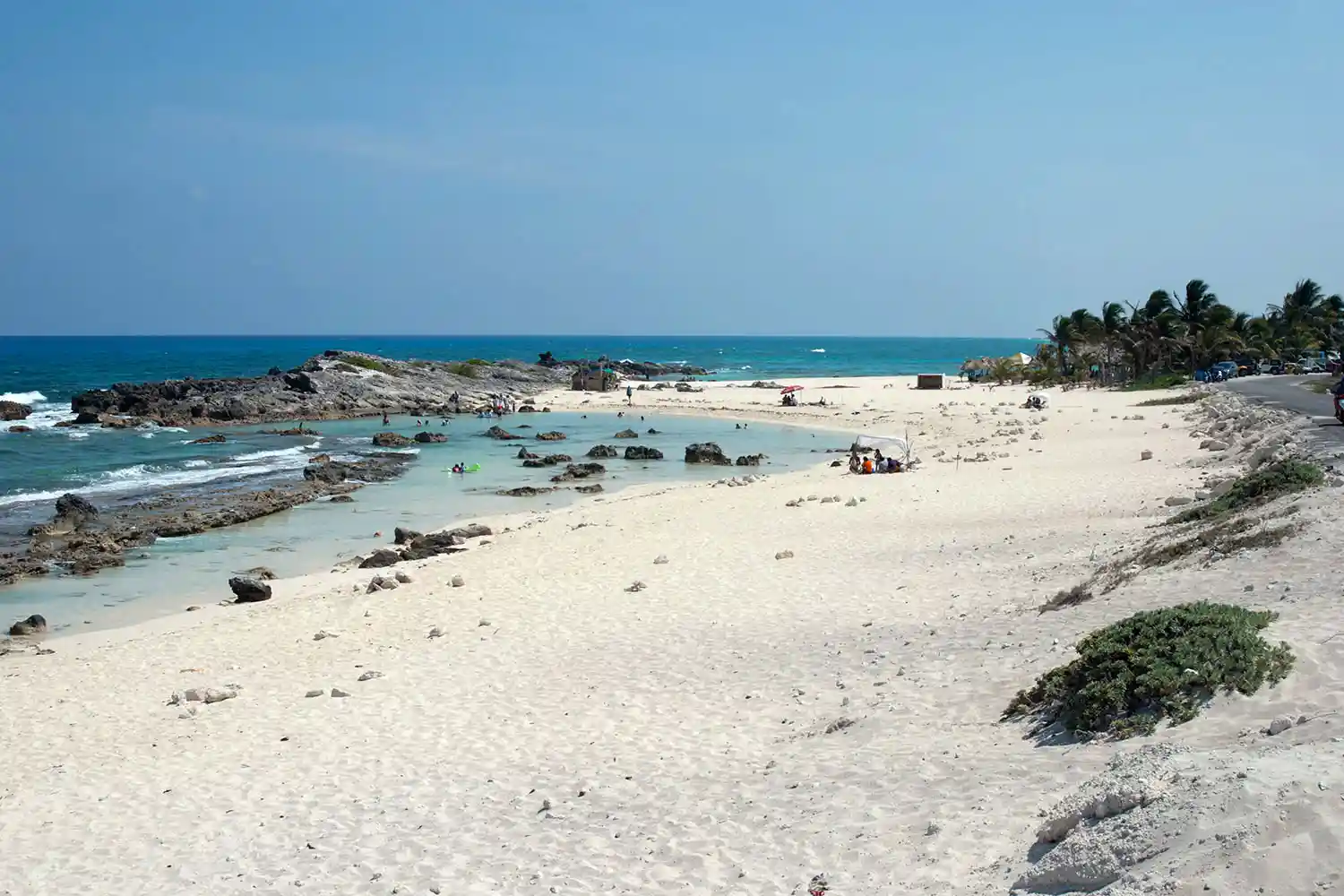 Waves crashing on the rocky east coast of Cozumel with an empty beach and coastal road