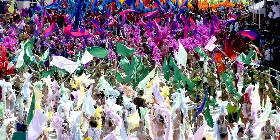 Masqueraders in colorful feathered costumes dancing in the streets during Trinidad Carnival