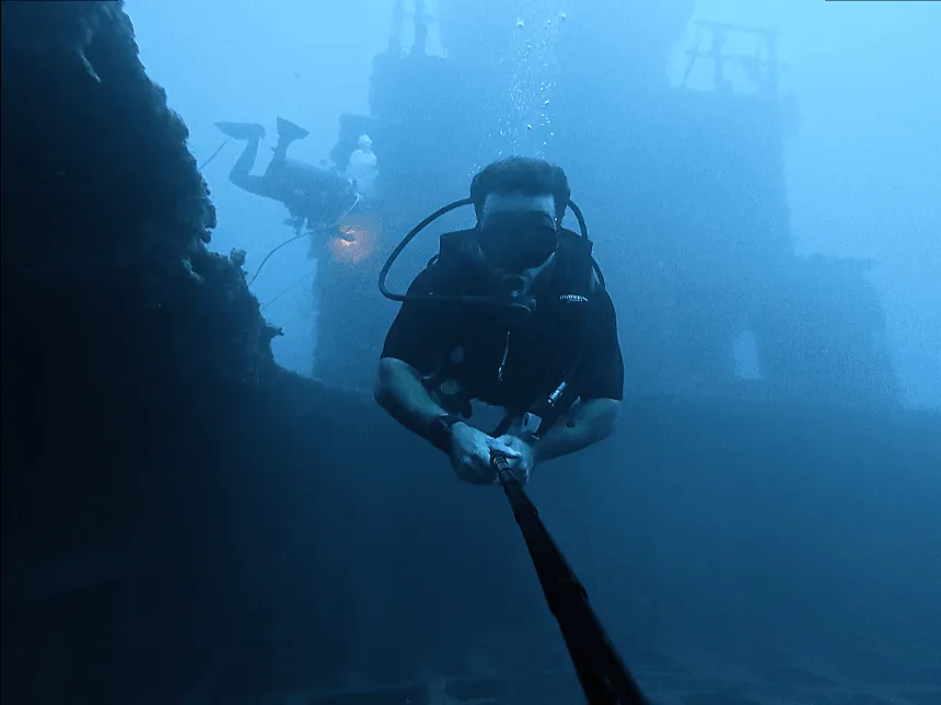 Freediver descending along a line into deep blue water off Utila