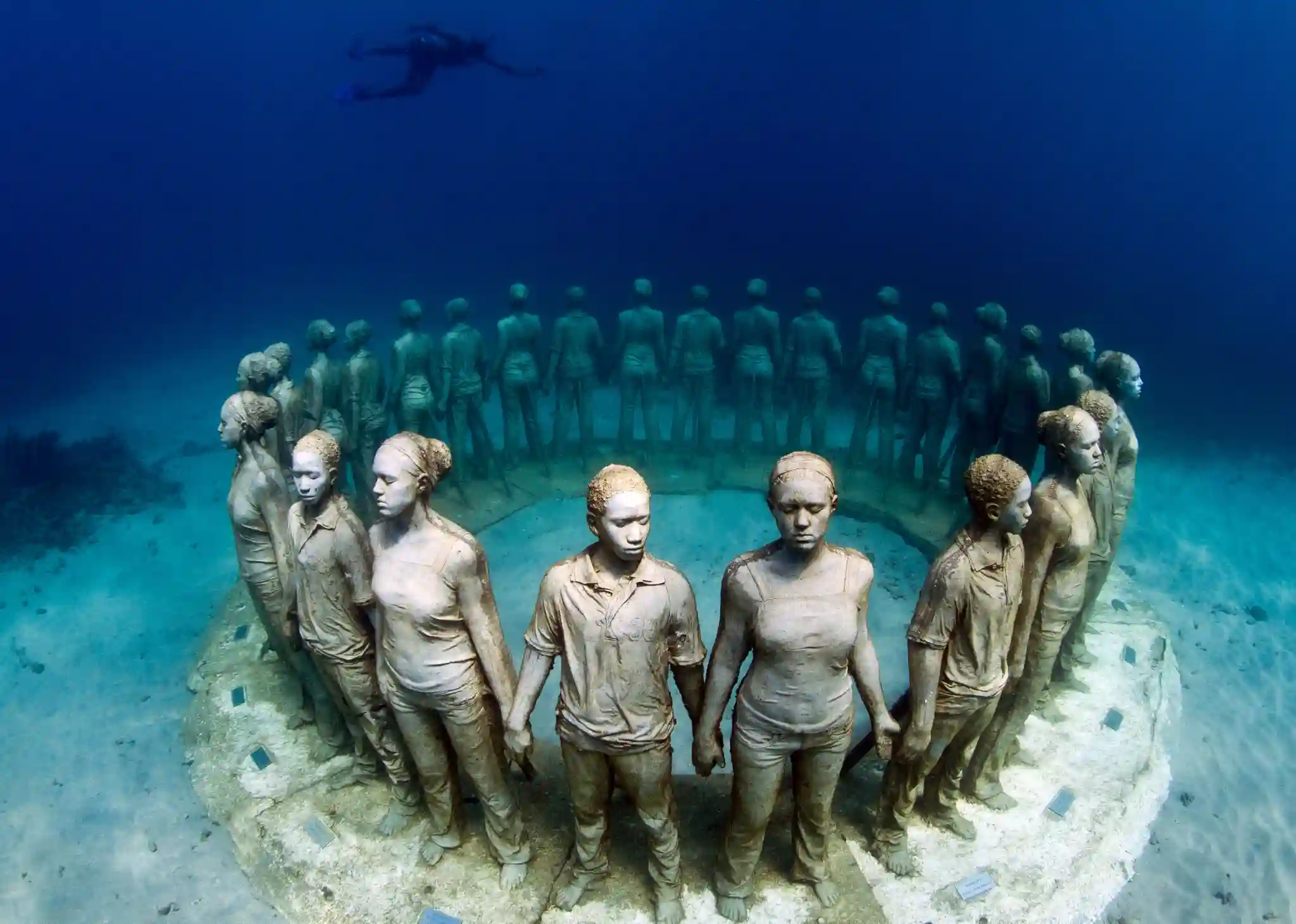 Ring of life-size concrete figures covered in coral on the seabed at the Underwater Sculpture Park, Molinere Bay, Grenada