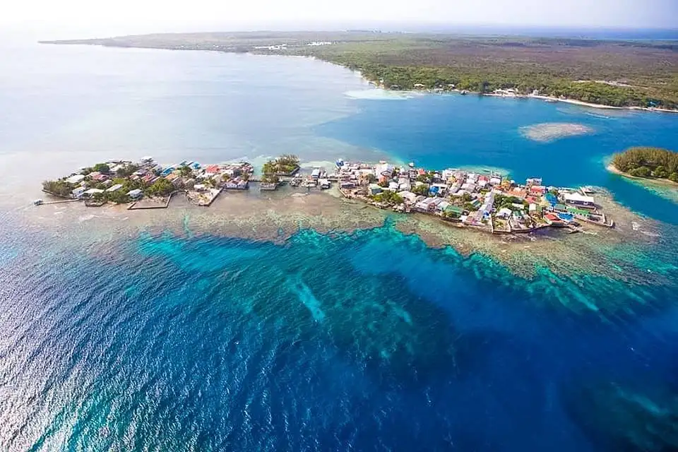 Tiny palm-covered Water Cay surrounded by white sand and turquoise water in the Utila Cays