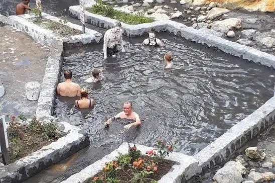 Visitors bathing in warm grey volcanic mud pools at Sulphur Springs near Soufriere, Saint Lucia
