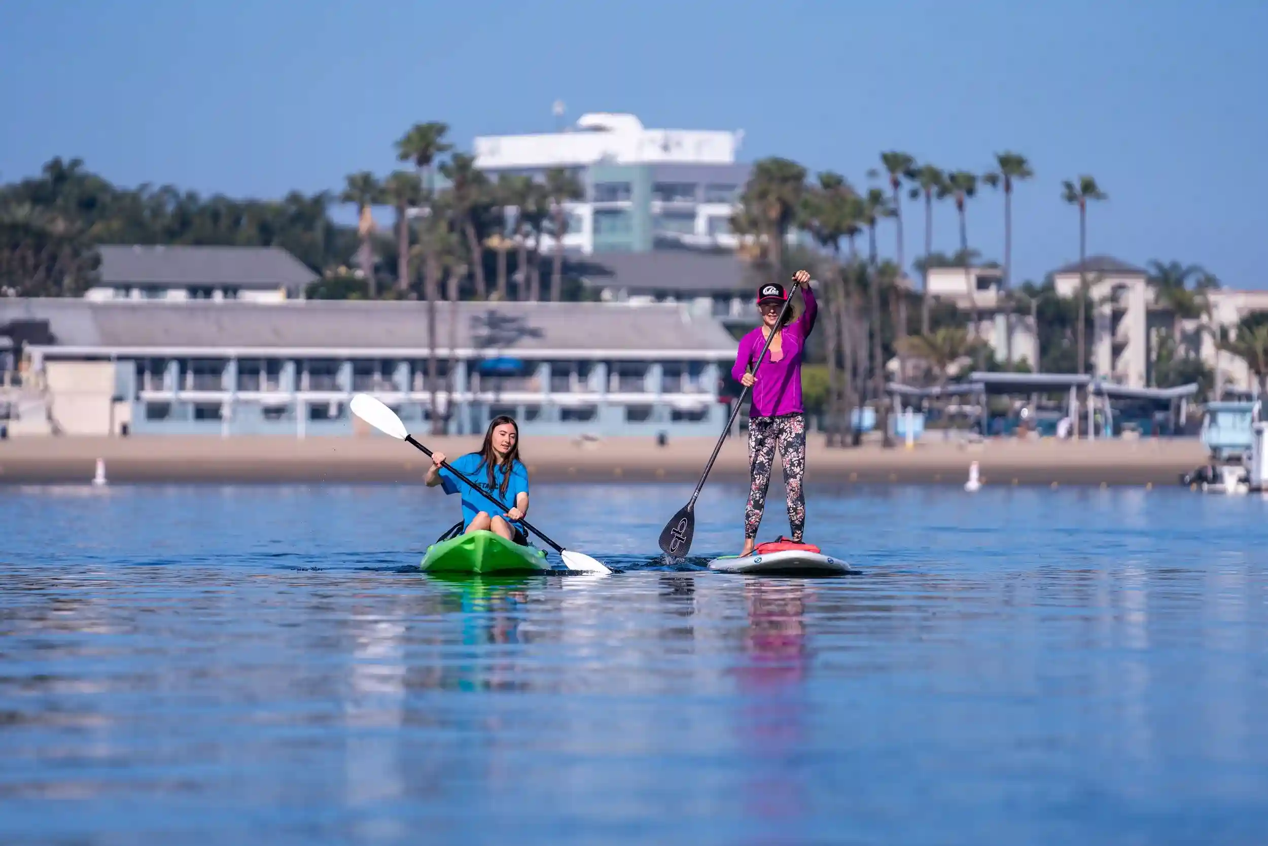 Stand-up paddleboarders gliding across the calm turquoise harbour water off Harbour Island